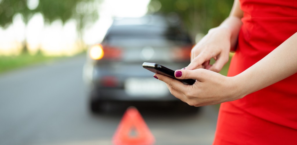 Woman standing behind car waiting for a tow truck