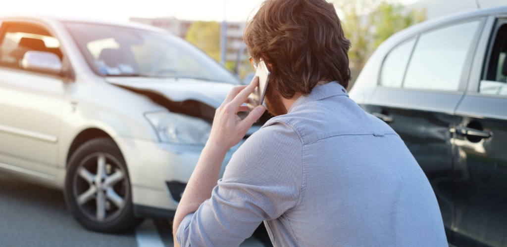 Man crouching next to a car after an accident